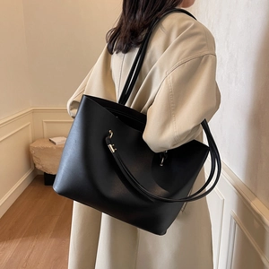 Borsa tote nera minimalista in pelle opaca mostrata indossata da una modella donna