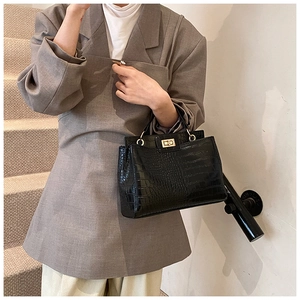 Close-up of black crocodile pattern leather handbag with gold metal twist lock buckle