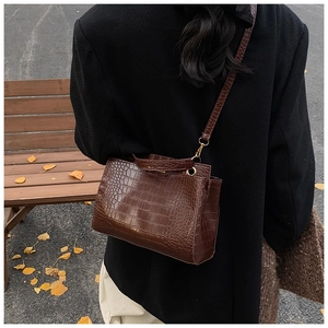 Outdoor lifestyle view of brown crocodile pattern shoulder bag on a model's arm