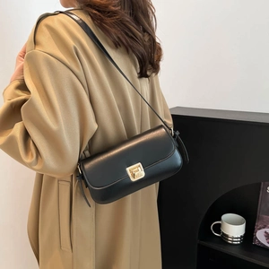 Minimalist black faux leather baguette bag with a gold buckle worn with a beige trench coat
