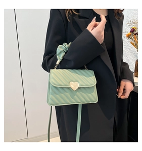 Dettaglio della borsa trapuntata verde menta con chiusura a cuore dorata e manico a nuvola
