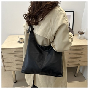 Borsa a tracolla nera minimalista abbinata a un trench beige per un look casual chic