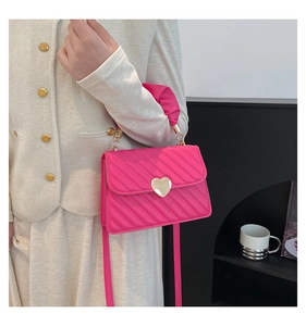 Dettaglio borsa trapuntata rosso rosa con chiusura a cuore dorata e manico avvolto in seta