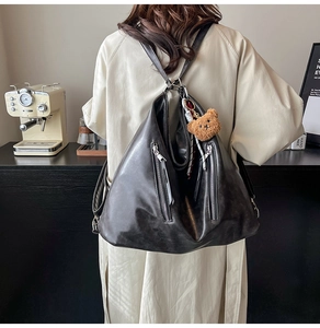 Detail of black faux leather backpack with vertical zippers and cute bear charm
