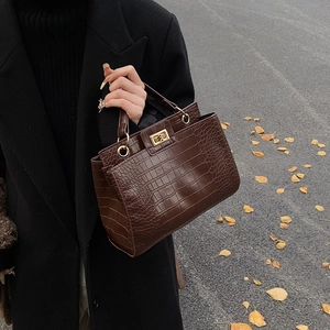 Brown crocodile embossed tote bag with gold metal buckle shown in street style fashion view