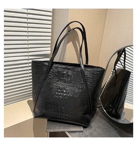 Detail of black tote bag with embossed crocodile texture and elegant double shoulder straps