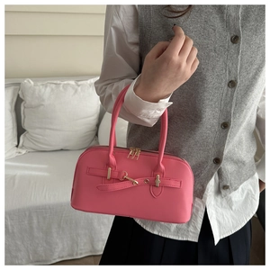 Detailansicht der rosa Handtasche aus Leder mit goldener Schnalle in Alltagsszene
