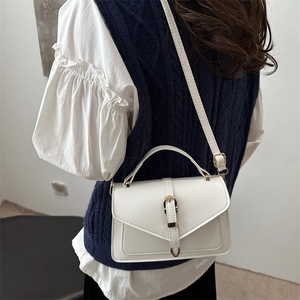 Petit sac carré blanc en cuir avec boucle dorée porté en bandoulière par un mannequin