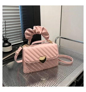 Dettaglio borsa trapuntata rosa con chiusura a cuore dorata e manico arricciato di tendenza