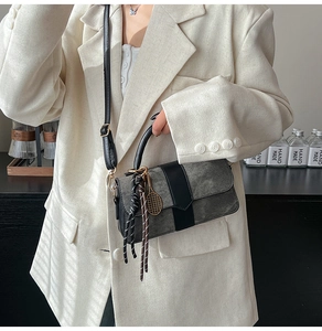 Detalle de bolso bandolera vintage con textura carbón y colgante de raqueta