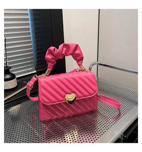 Dettaglio della mini borsa trapuntata rosa con chiusura a cuore oro e manico morbido