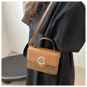 Detail showing the brown patchwork leather and canvas crossbody bag with silver M logo