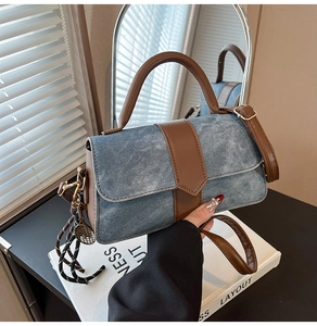 Detalle del bolso de tela vaquera azul y cuero marrón con colgante de raqueta