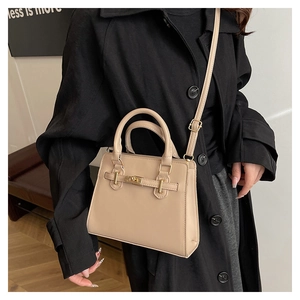 Detail of elegant beige crossbody bag showing golden buckle and adjustable strap