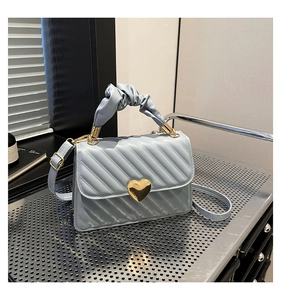 Dettaglio della borsa trapuntata azzurra con chiusura a cuore dorata e manico a scrunchie