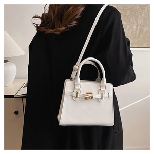 Detailed side view of white minimalist handbag with gold twist lock and black coat contrast