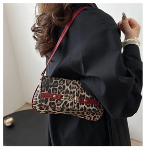 Détail du sac léopard avec bandoulière rouge et boucle dorée porté par le mannequin