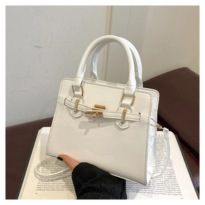 Detail of white leather handbag with golden square lock and elegant trapezoid shape