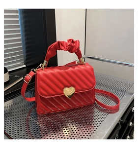 Dettaglio della borsa in pelle trapuntata rossa con chiusura a cuore dorata