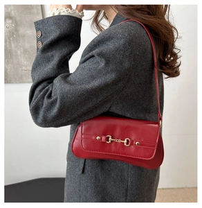 Détail du sac porté épaule rouge vintage avec boucle dorée sur blazer en tweed gris