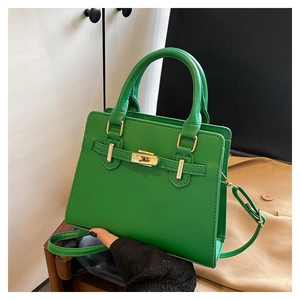 Detail of green leather handbag featuring golden twist lock and signature strap design