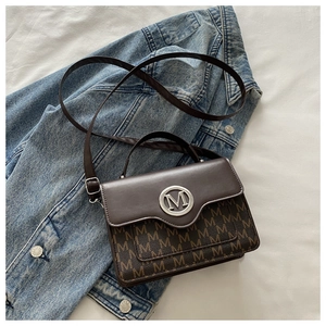 Detail of dark brown leather handbag with silver M buckle and monogram over denim fabric