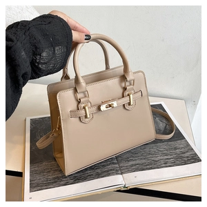 Detail of light beige tote bag with gold metal twist lock and structured leather texture