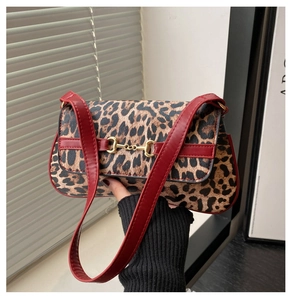 Détail du sac à imprimé léopard avec bordure en cuir rouge et boucle mors dorée