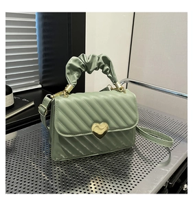 Dettaglio borsa trapuntata verde salvia con chiusura a cuore oro e manico arricciato