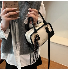 Detail of minimalist two-tone shoulder bag with top handle and fashion logo print
