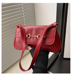 Détail du sac baguette rouge avec boucle mors dorée classique tenu par une personne