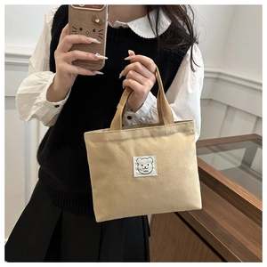 Model holding a mini khaki canvas bucket bag featuring a cute bear patch and LUNA text