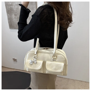 Nahaufnahme der cremefarbenen Ledertasche mit silbernem Schleifenanhänger und Details