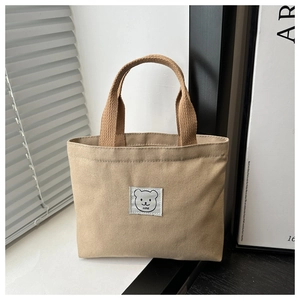 Detailed macro view of khaki canvas bucket bag with cartoon bear embroidery patch