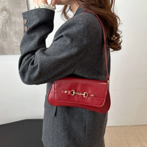 Sac baguette rouge vintage avec boucle mors dorée sur un blazer en laine gris