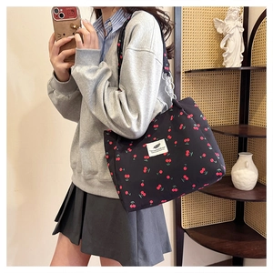 Close-up of black tote bag with red cherry print and stylish metal chain shoulder strap