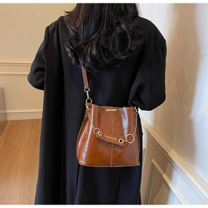 Detail of vintage brown bucket bag with gold chain strap and fashion pendant