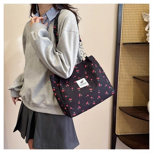 Detail of black canvas tote bag with cherry print and metallic chain shoulder strap