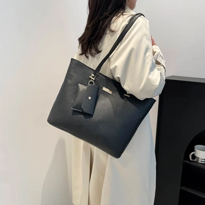 Grande borsa tote nera minimalista con trama a grana e ciondolo per pendolari urbani