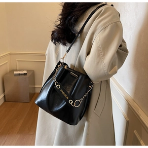 Detail shot of black leather bucket bag with gold chain and branded fashion strap