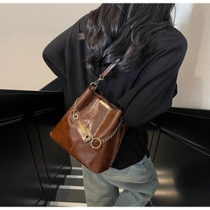 Detailed macro view of brown oiled leather texture and gold chain on bucket bag