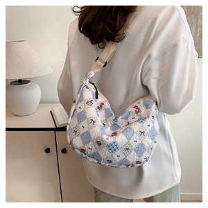 Quilted crescent tote bag with blue checkered pattern and bear print shown on shoulder