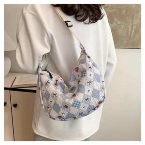 Close-up of quilted light blue bear print crescent bag with adjustable wide strap