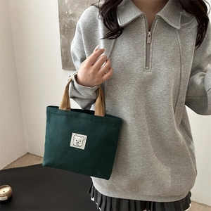 Minimalist dark green canvas bucket bag with woven handles and cute bear logo print