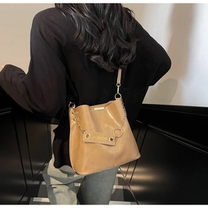 Detail of caramel leather bucket bag featuring gold chain and FASHION leather tag