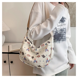 Detail of cream crescent shoulder bag featuring cartoon elephant prints and pleated texture