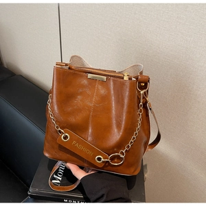 Detailed close-up of dark brown bucket bag with gold accents and fashion charm