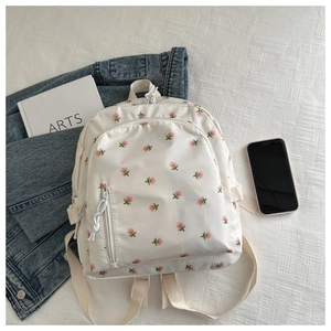 Detailed view of cream-white floral backpack with pink flowers on a textured background