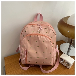 Detailed view of pink backpack with floral embroidery on wooden table with vintage decor