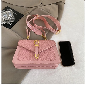 Detail of pink handbag with woven texture flap and golden buckle on stylish crossbody strap